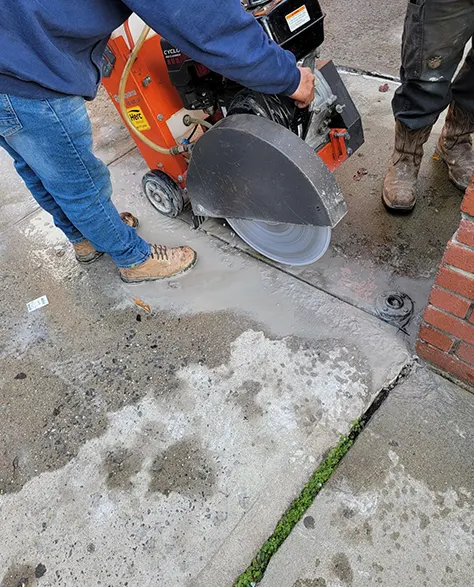 A Zavza Seal LLC expert cutting a concrete sidewalk for raising with specialized equipment<br />
