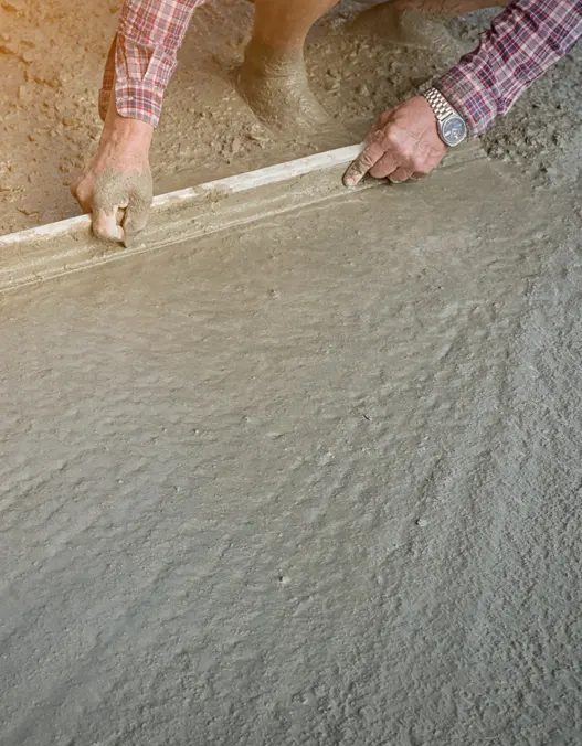 construction workers laying new concrete slab and leveling it 