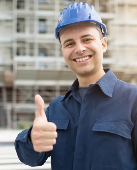 A contractor in a hard hat giving a thumbs up in a construction site 