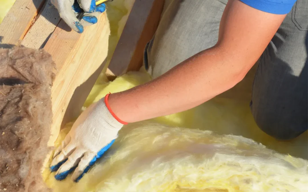 Contractor wearing white and blue gloves putting yellow insulation in place