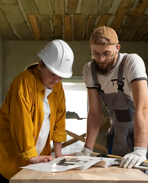 Contractors hunched over a blue print on a desk 