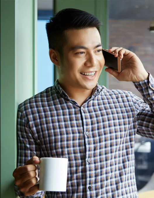 A man holding a cup and talking on the phone to make an appointment for concrete installation and pouring 