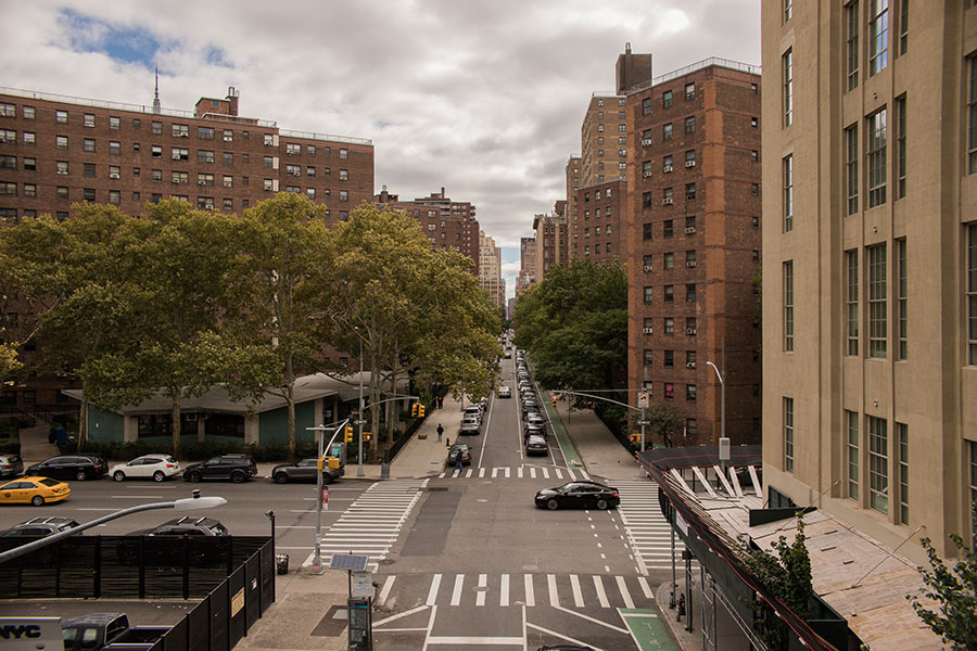 Skyline of Bronx, NY with tall bricked buildings on either side of a busy road