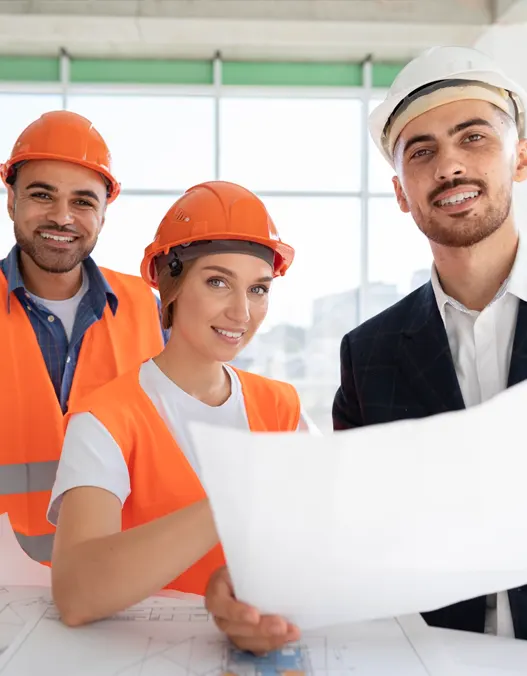 Three contractors in hard hats and reflective vests. One holding a blue print