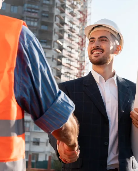 Two contractors shaking hands on a construction site