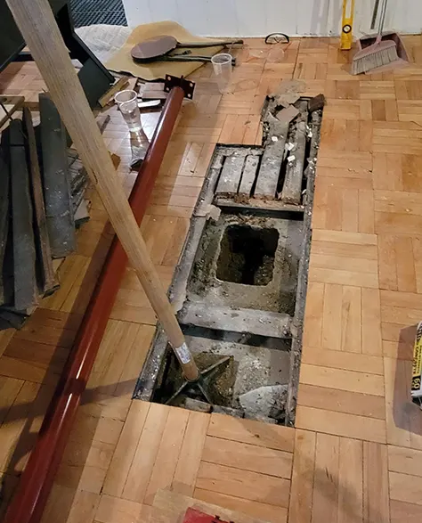 A contractor adjusting a lally column in a residential basement.