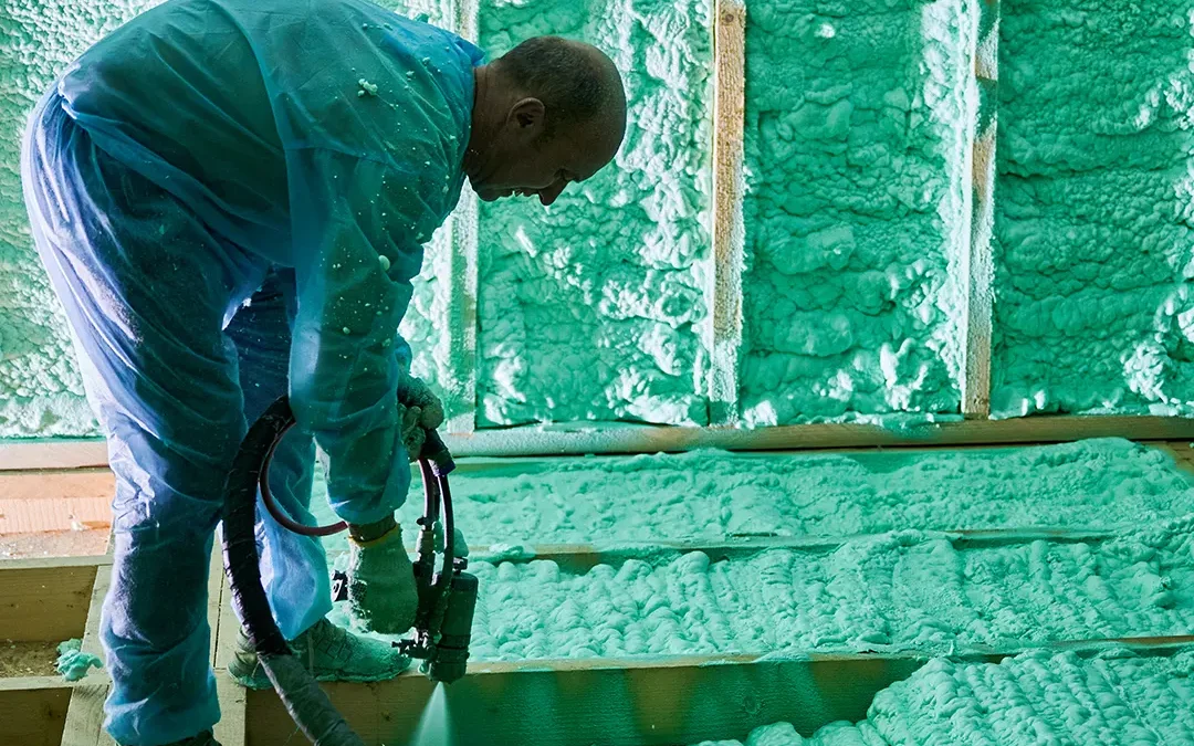 A contractor in a protective suit installation open-cell spray foam insulation