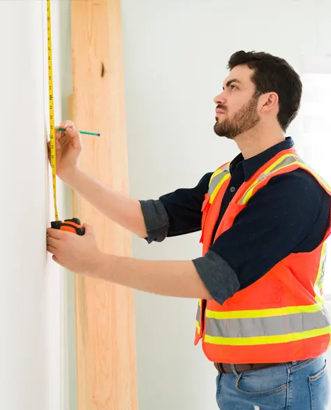 A contractor measuring a wall with a measuring tape