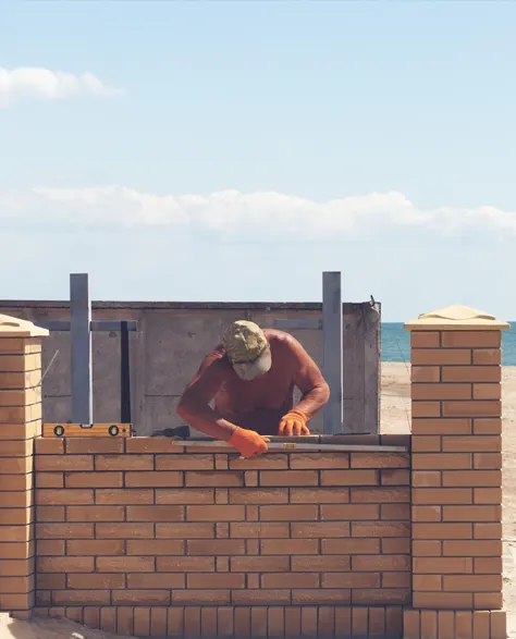 A man building a retaining wall on a coastal property.