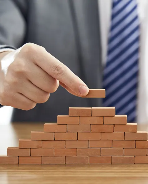 A man in a suit putting small bricks together depicting setting up a strong foundation