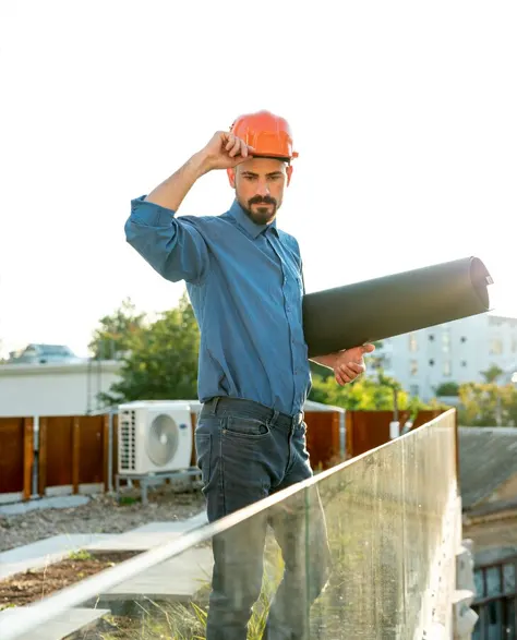 A professional contractor in a hard hat holding a blueprint under his arm 