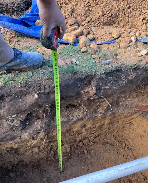 A Zavza Seal expert measuring the depth of the ground where the dry well system will be installed