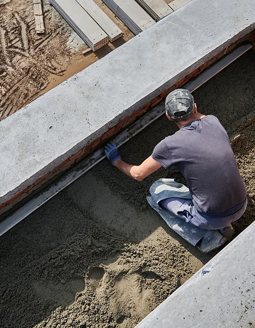 A man laying the concrete foundation of a commercial building 