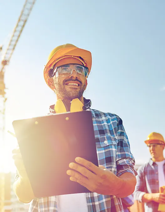 A professional contractor holding a blueprint in a construction site