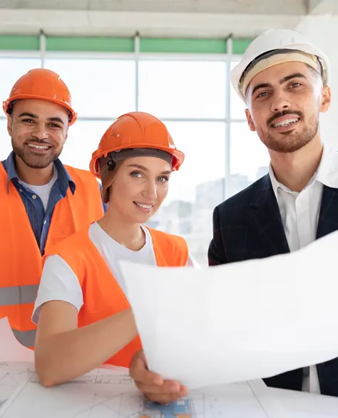 Three contractors in hard hats and reflective vests, one holding a blueprint