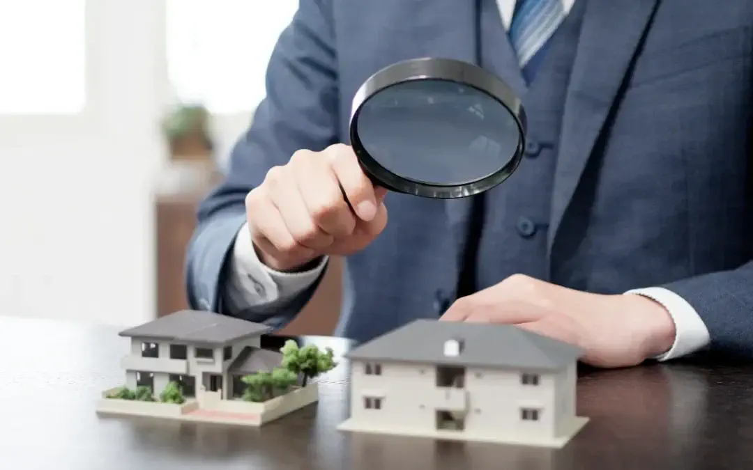 Foundation Cracks - A Man Holding a Magnifying Glass Over a Small House Model on the Table