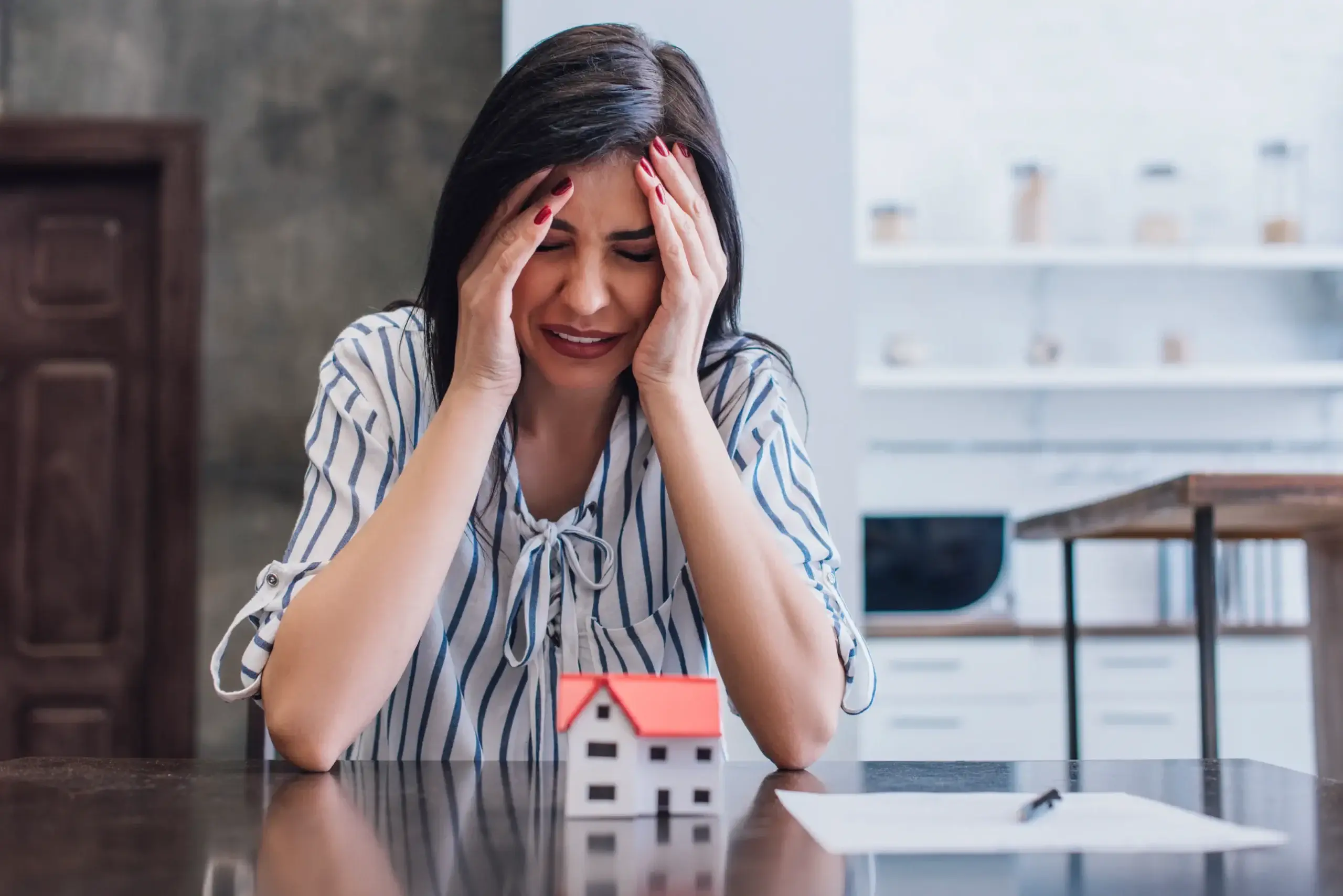 Is Your Builder Responsible for Foundation Problems? - A Homeowner Holding Her Head at the Table, Upset About Something