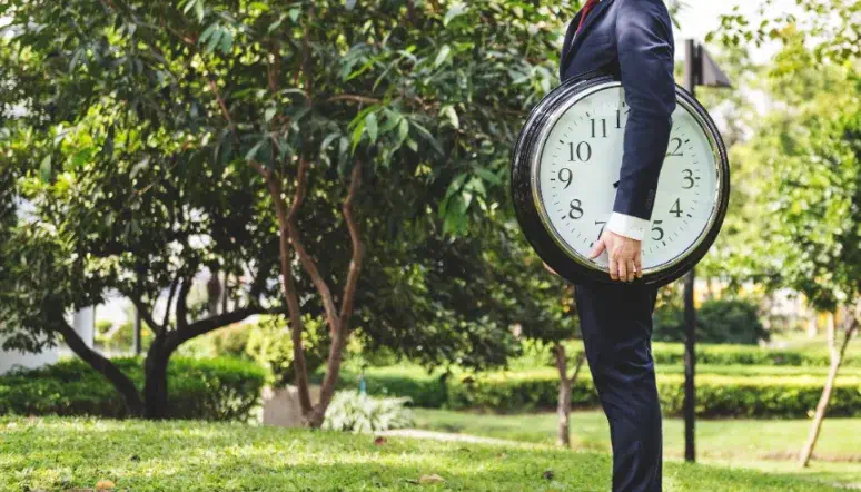 How Long Do French Drains Last - A Man in a Field Holding a Huge Clock Under His Arm