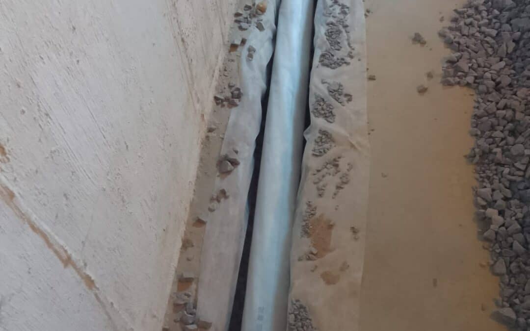 Best Rock for French Drain - A French Drain Install in a Crawl Space in Brooklyn with the Trench Dug and Rocks Nearby and the Pipe Showing
