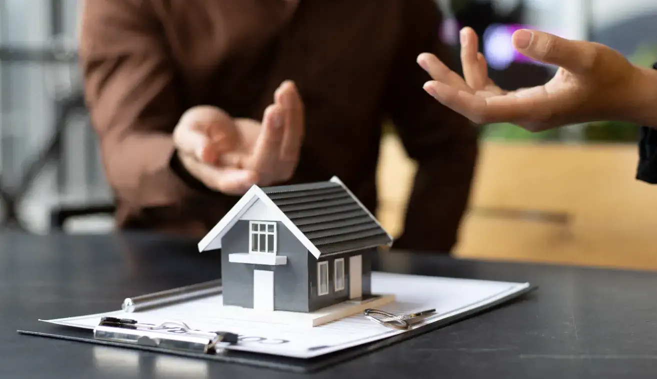 Can You Sell a House with Structural Damage - A House Model Sitting on a Table Where Two People Are Negotiating