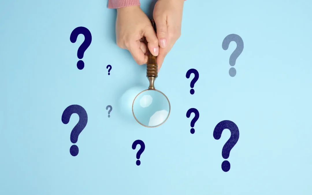 What Types of Mold Are in a Crawl Space? - A Woman’s Hands Holding a Magnifying Glass Over a Light Blue Surface with Dark Blue Question Marks on it