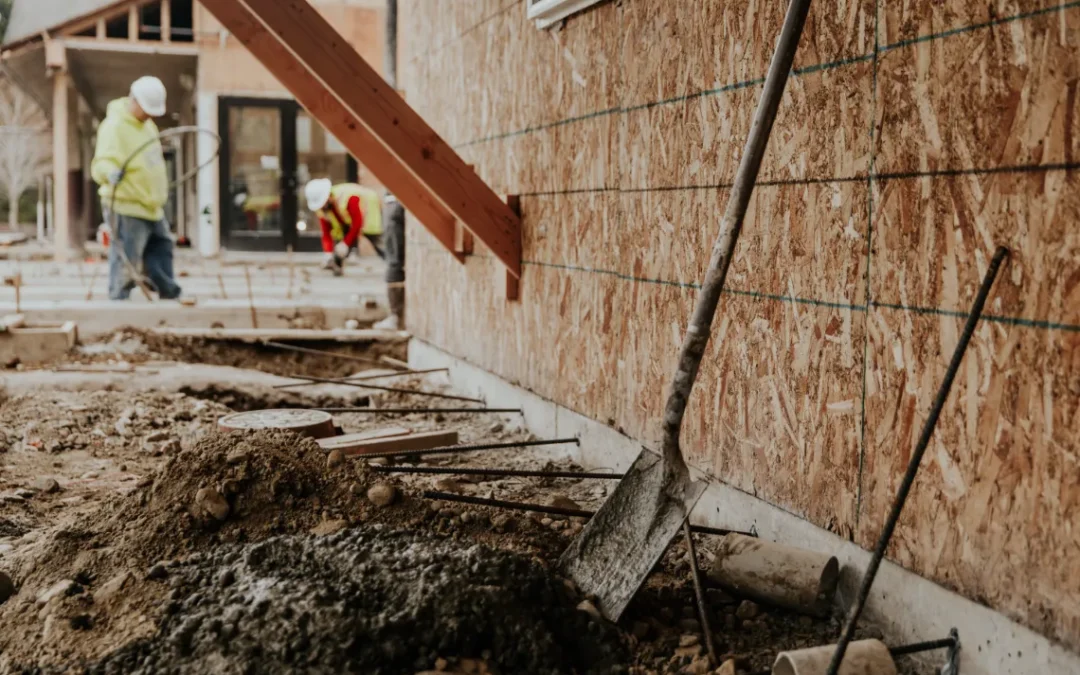 What is Foundation Settlement - A Picture of a House with the Foundation Dug Out and Construction Workers Working Nearby