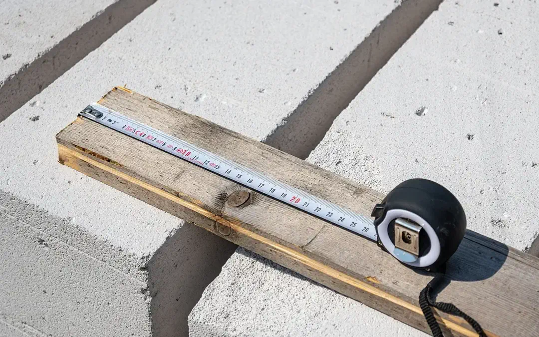 A measuring tape and level placed on top of two foundation slabs