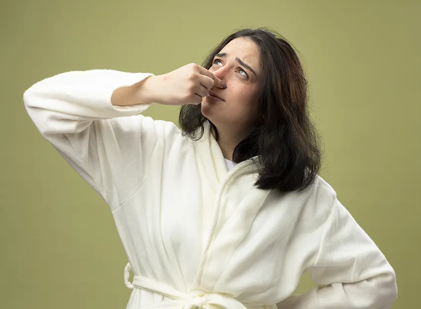 A woman holding her nose to avoid the sewer odor in house.