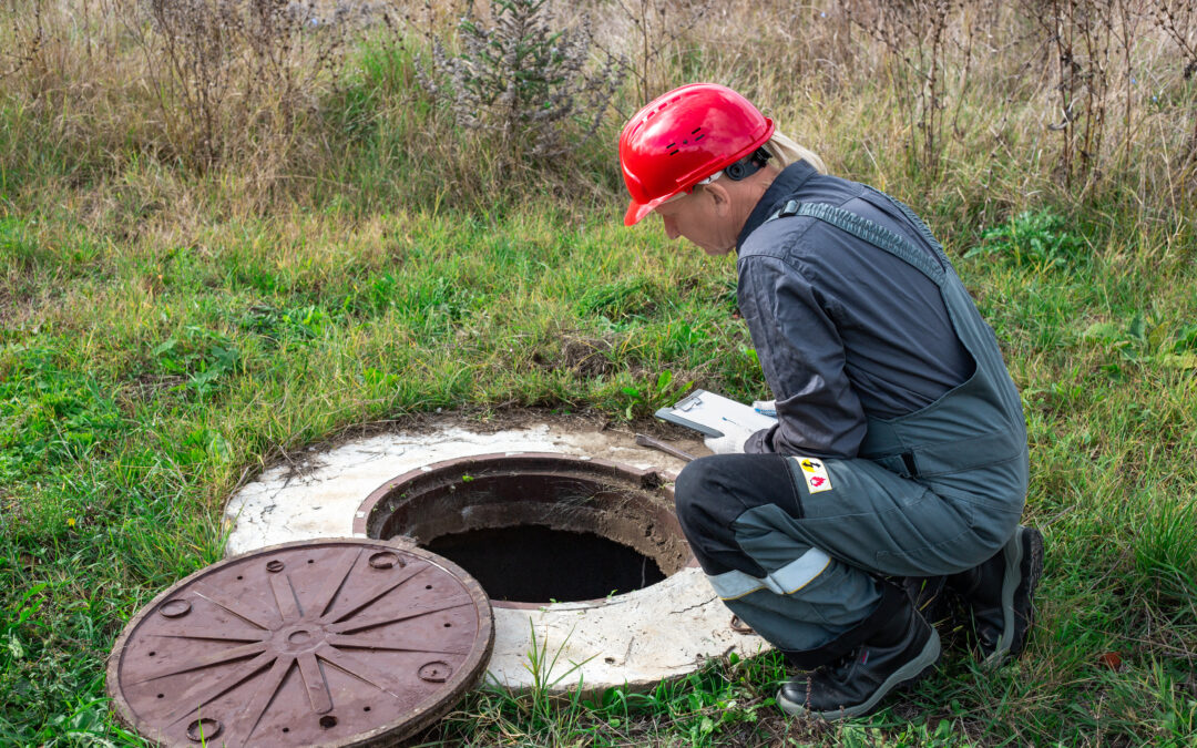 A contractor kneeling over an open drain