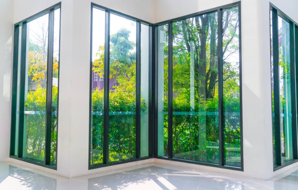 A modern glass window that is overlooking a beautiful green garden