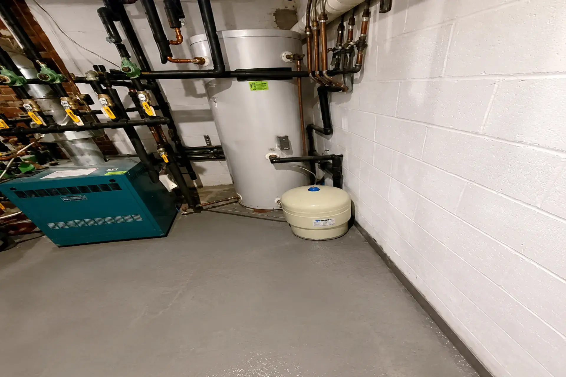 completed-basement-waterproofing-featured Finished basement waterproofing project in Halesite NY with interior drainage system, restored concrete floor, and cinder block foundation repair.