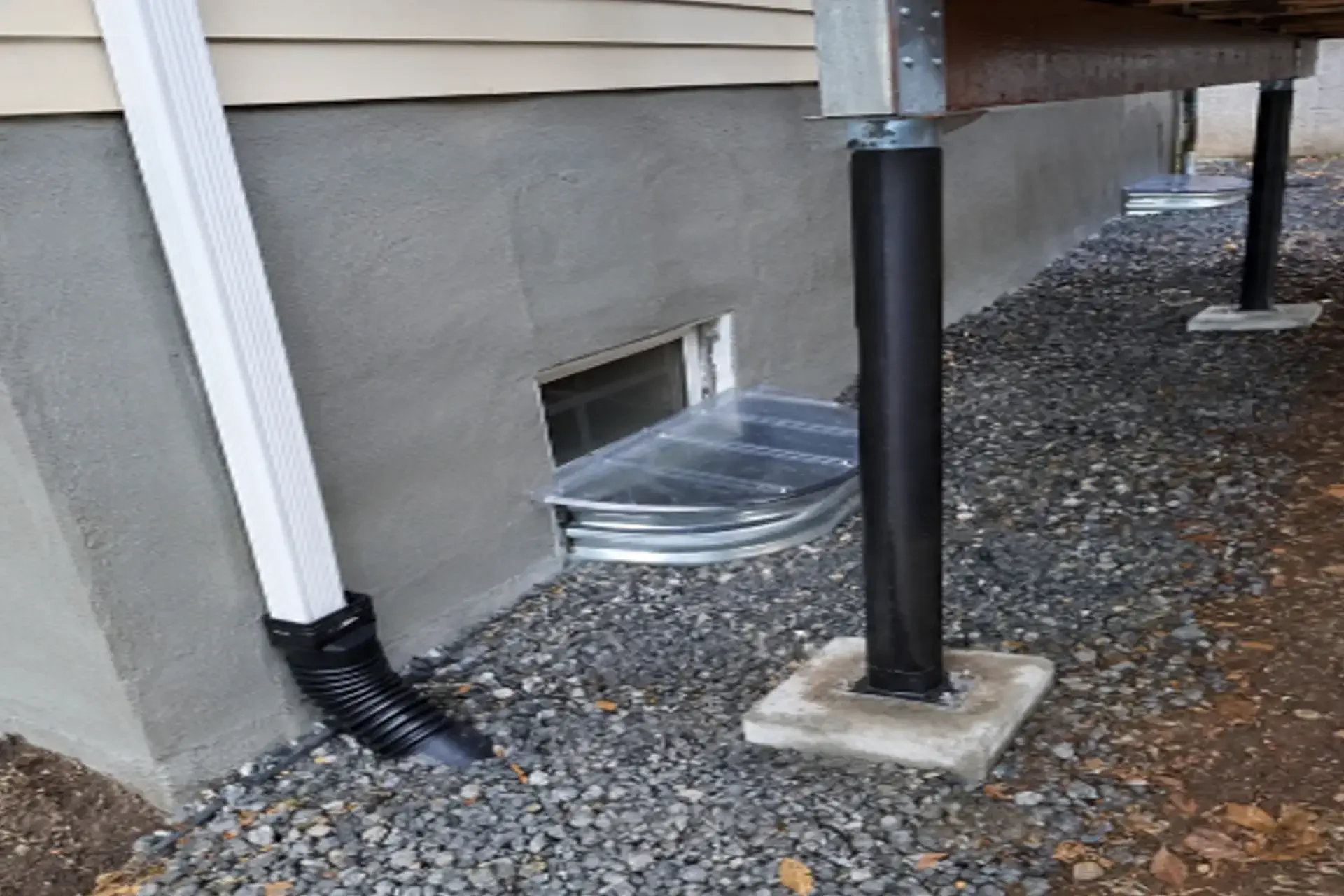 foundation-drainage-and-structural-stabilization-featured Foundation drainage and structural stabilization in Lloyd Harbor, NY showing completed downspout system, foundation repairs, & waterproofing concrete surfaces.