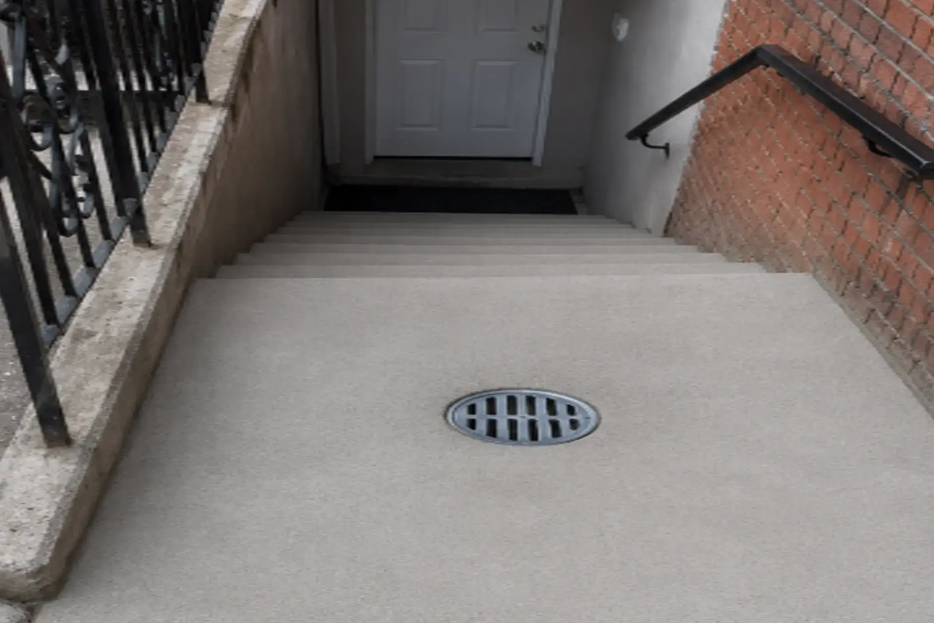 new-reinforced-concrete-featured Completed stairway bottom landing drainage repair in Brooklyn NY featuring a new stormwater drain, reinforced concrete slab, and improved water management system.
