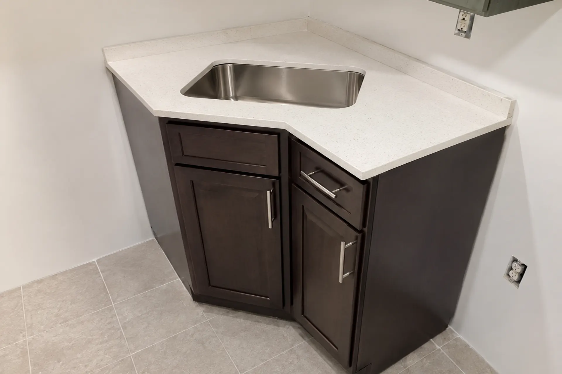 Completed kitchen repair in Brooklyn, NY featuring a newly installed corner sink cabinet, repaired floor area, and updated plumbing.