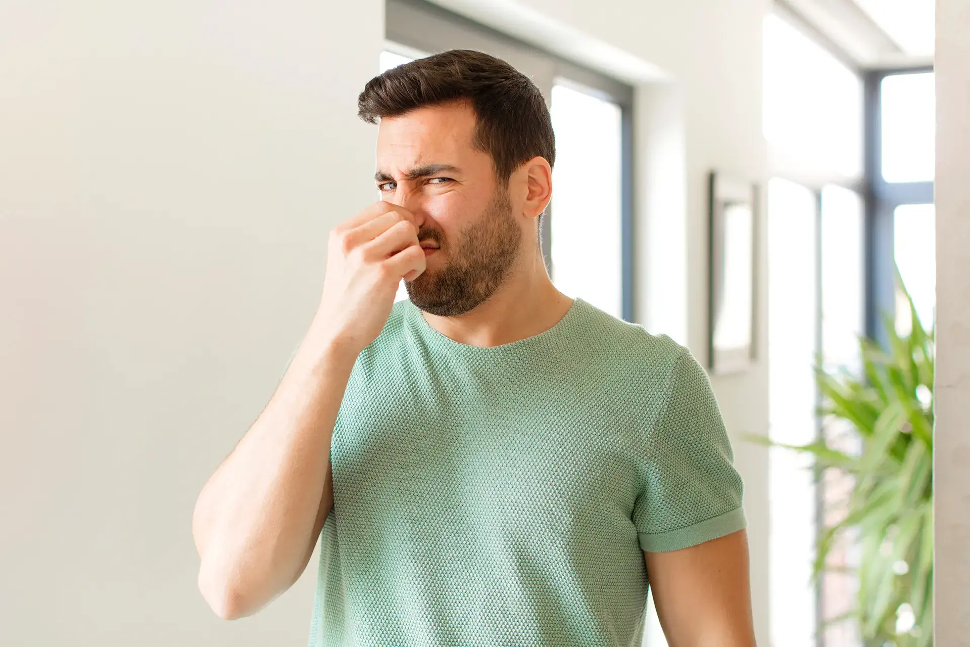musty-smell-in-the-property A man entering a propetry to buy and holding his nose because of the strange, musty smell in the property in a home in Brooklyn, NY