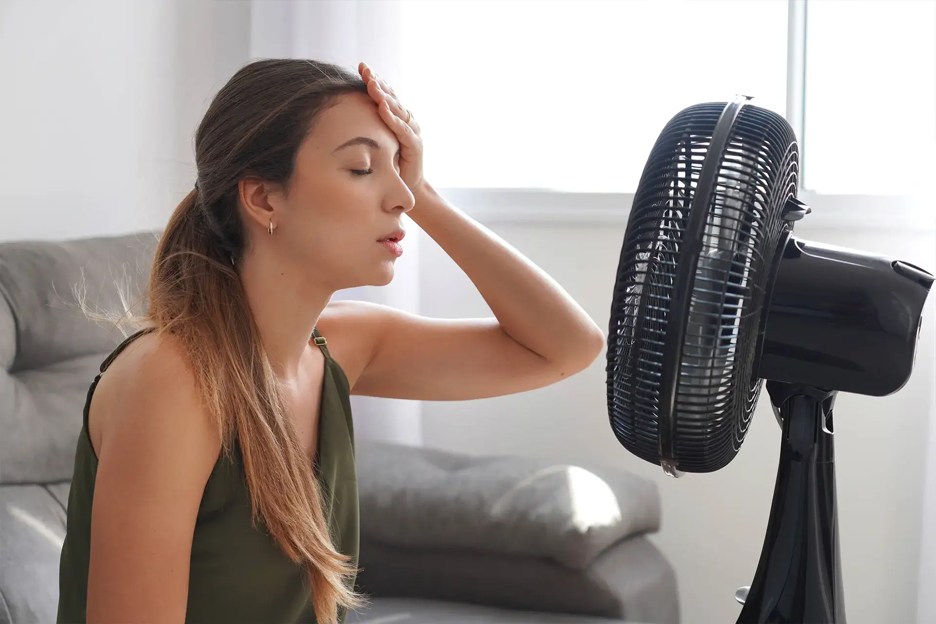 an overheated woman in a hot home where her insulation in not working 