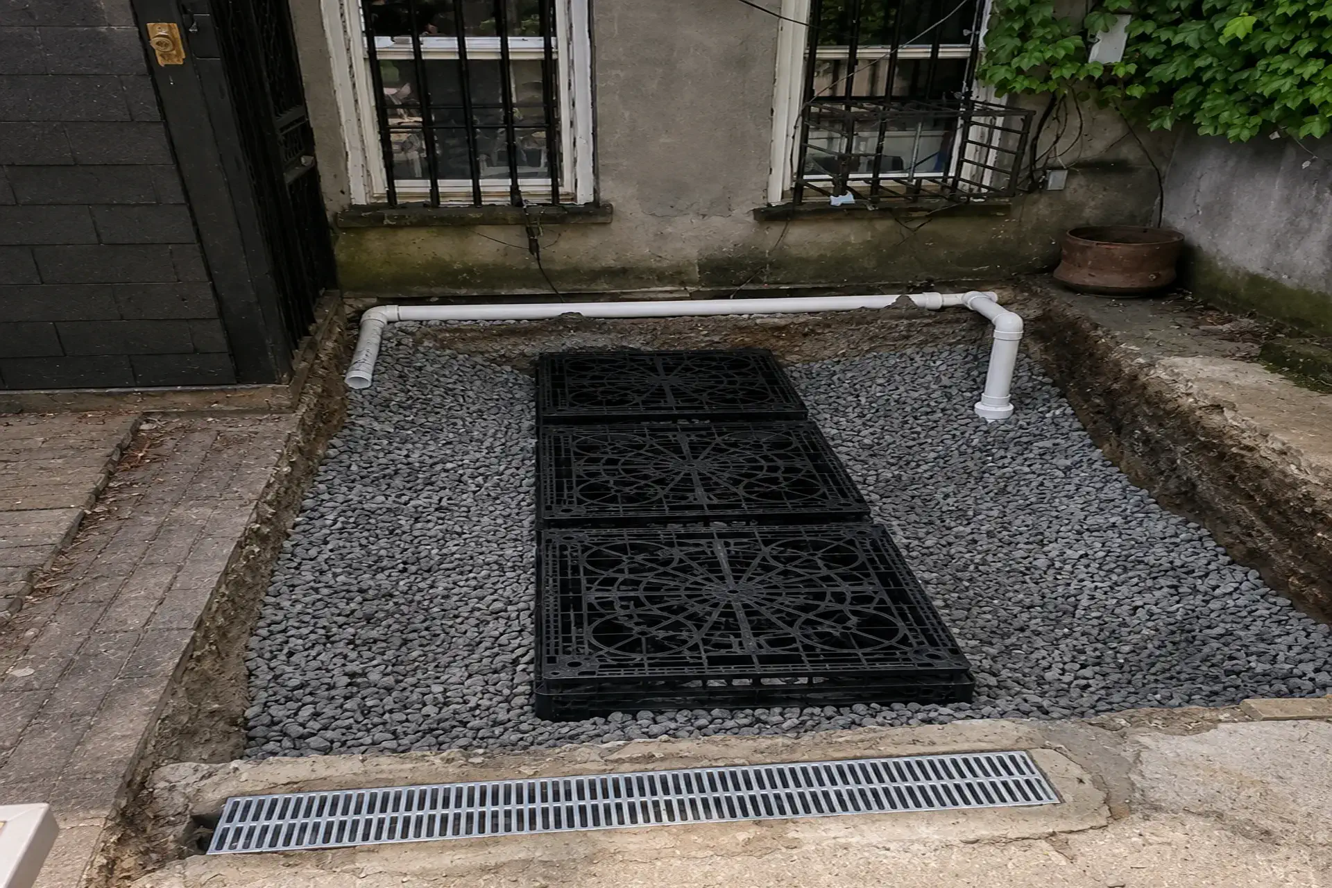 completed-backyard-stormwater-drainage-system-featured Completed backyard stormwater drainage system with storm channels near the back door of a Brooklyn NY residential property.