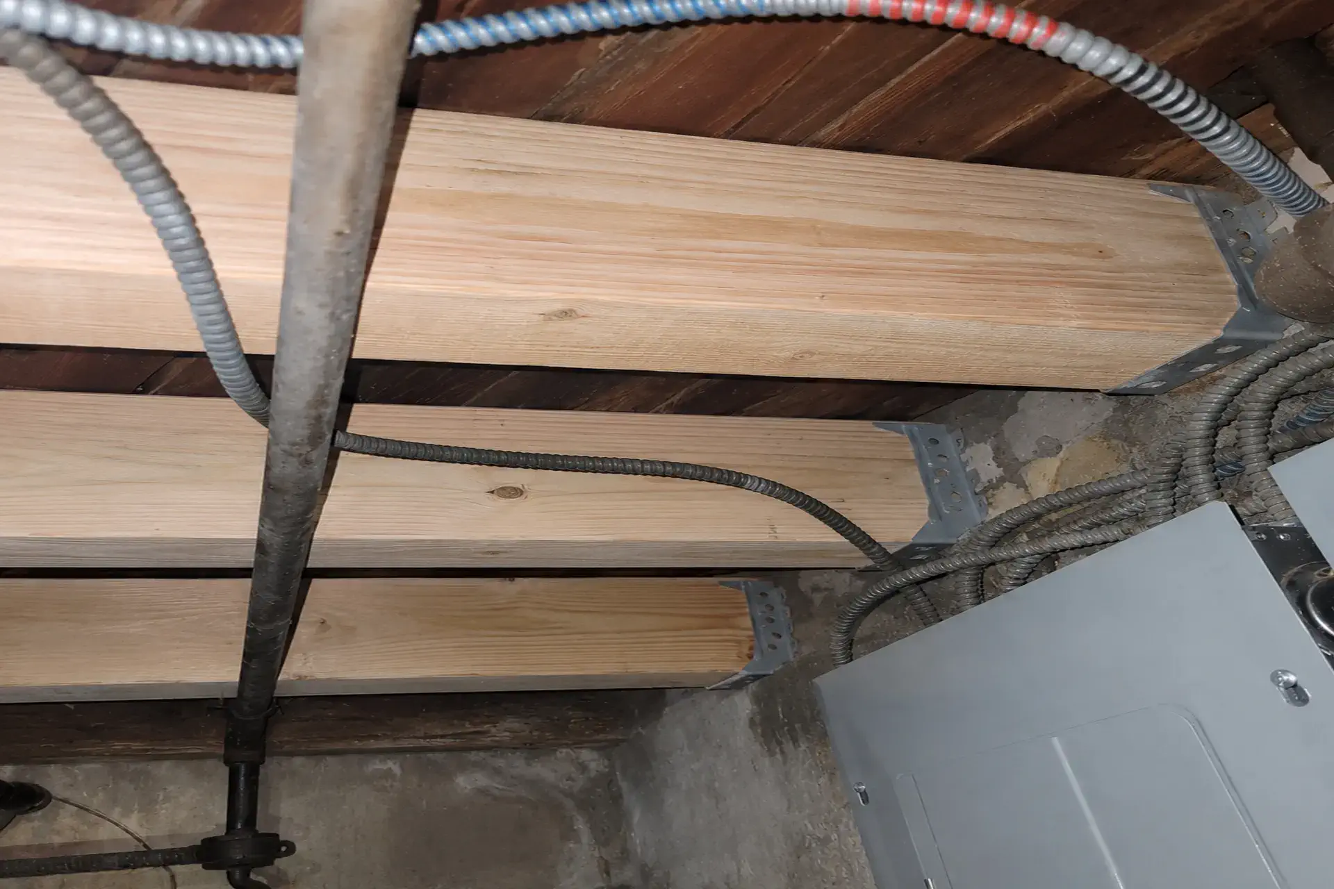 Completed floor joist structural repair in Brooklyn, NY featuring sistered lumber, wood restoration, and galvanized steel reinforcement.