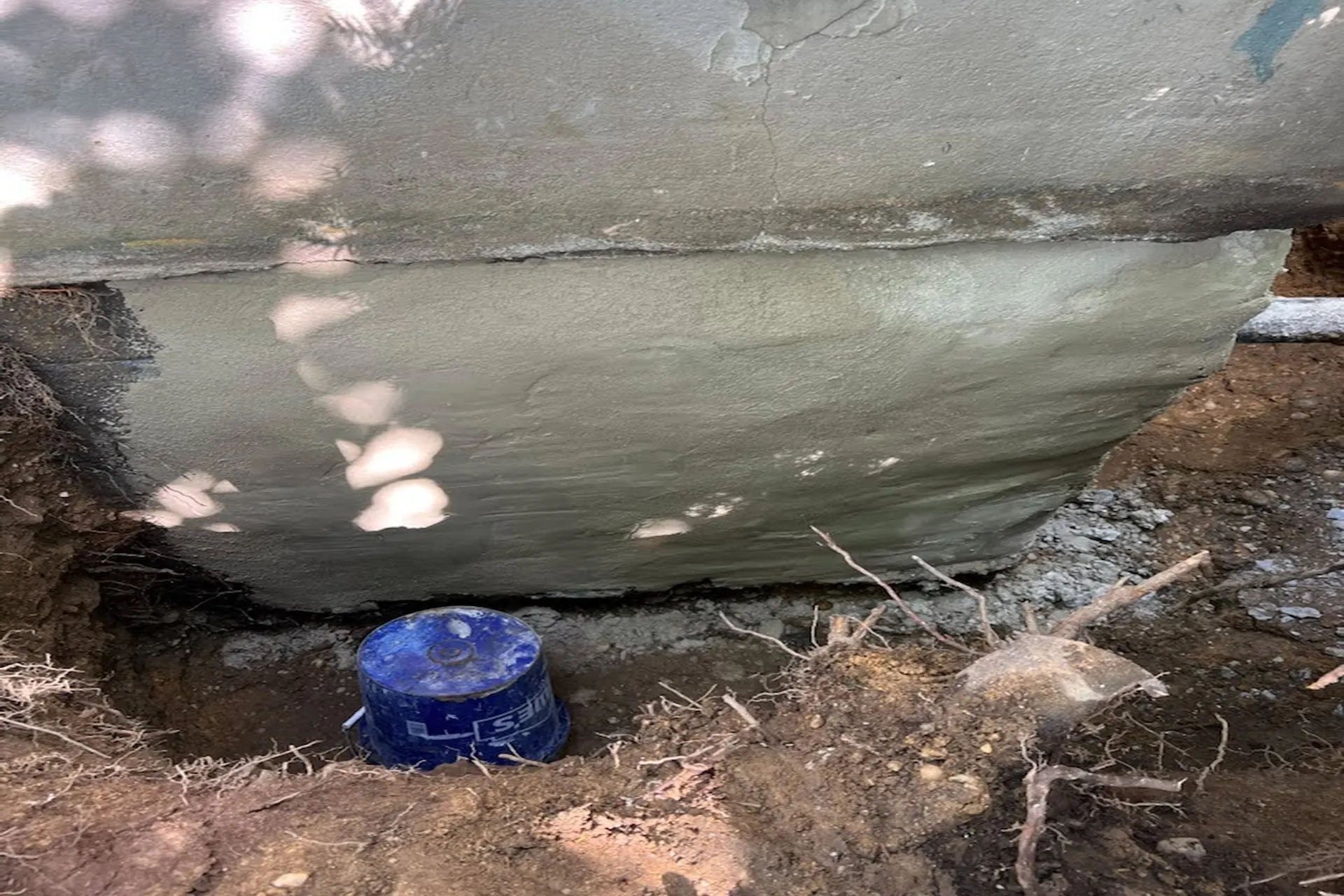 exterior-foundation-waterproofing-graded-drainage-after Exterior foundation waterproofing and downspout drainage repair in progress on an Islip NY residential property.